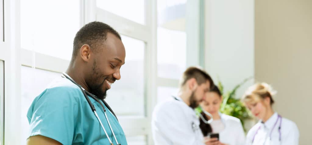 Healthcare people group. Professional african american male doctor with phone posing at hospital office or clinic. Medical technology research institute and doctor staff service concept. Happy smiling